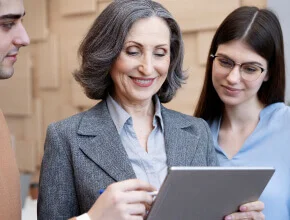 An experienced female executive and a younger colleague reviewing a digital tablet, showcasing the mentorship and technical proficiency within IT and BPO services.