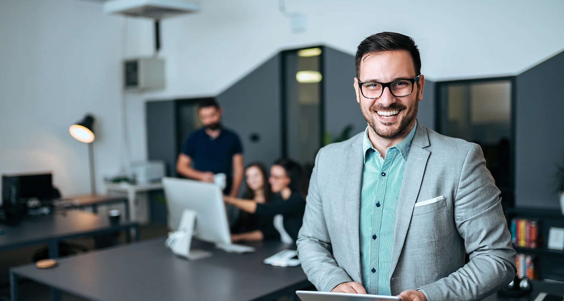 A tech-savvy professional holding a tablet and smiling, showcasing the modern technology and innovation behind our IT and BPO services.